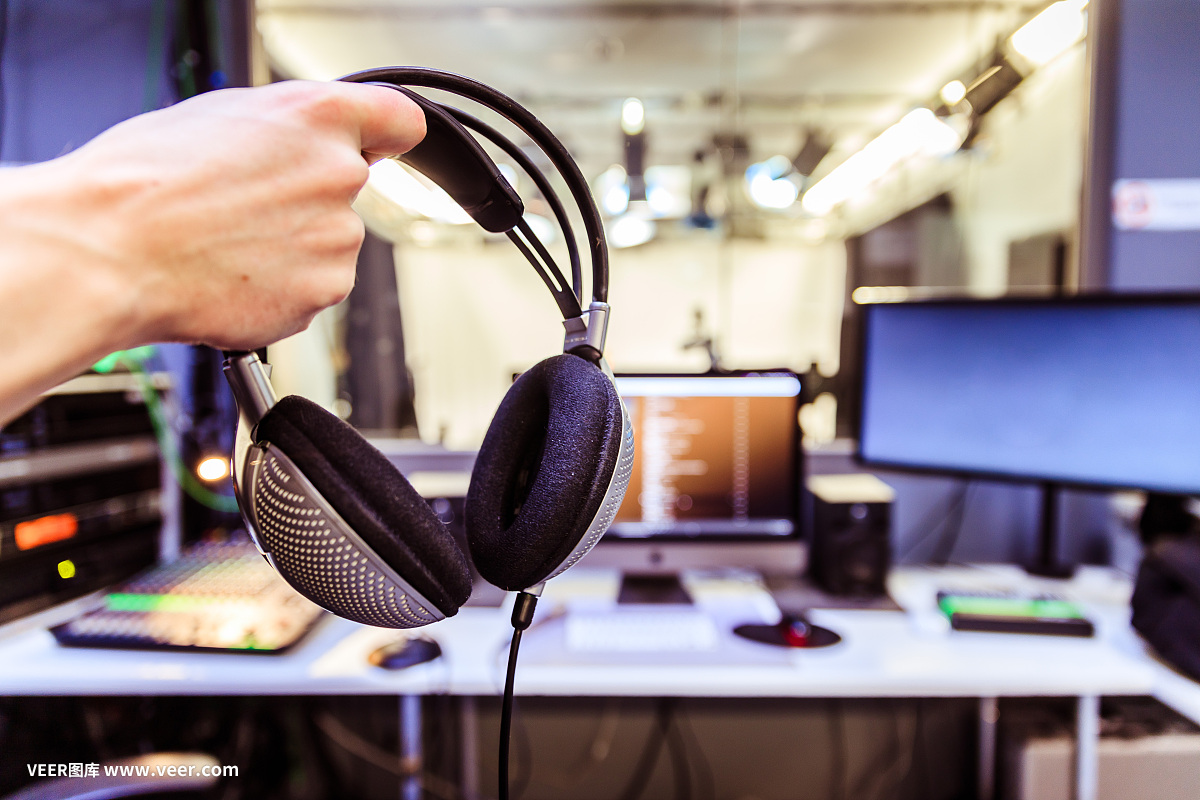 錄音室錄音:一個戴著耳機(jī)的年輕人正坐在錄音室里,錄音室的背景模糊不清
